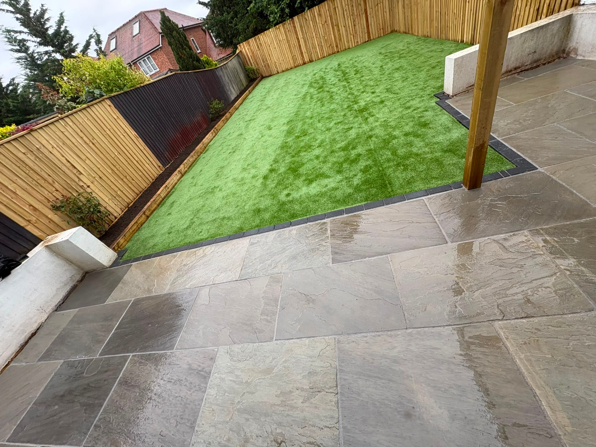 Grey sandstone patio with charcoal edging, new lawn and close-board fencing in a Berkshire garden